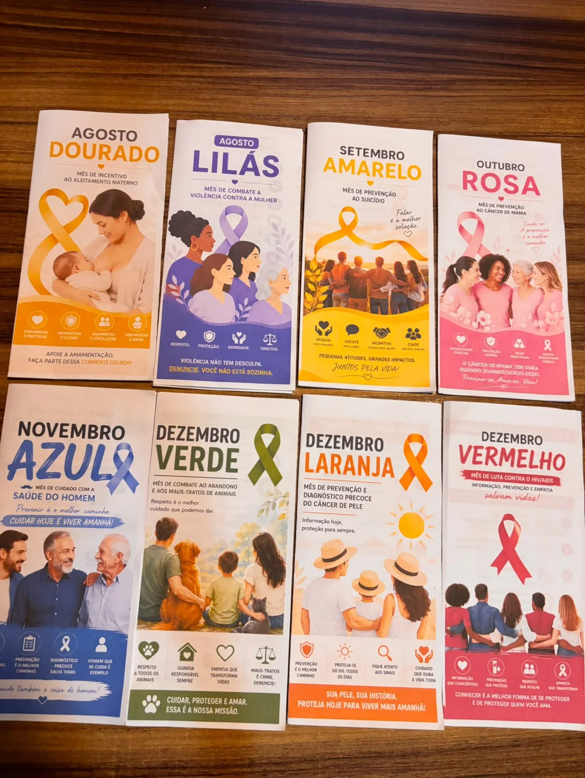 Os 8 folders do combo impressos e organizados sobre uma mesa de madeira